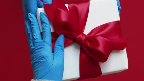 Hands in Gloves Holding a Gift Box