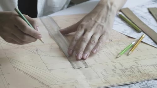 Architect using ruler and pencil to make blueprints on old paper. Engineer works with blueprints