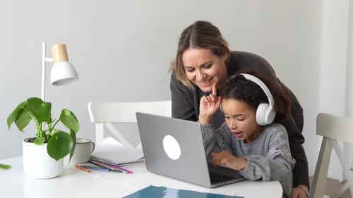 Woman and Child Using Laptop at White Table
