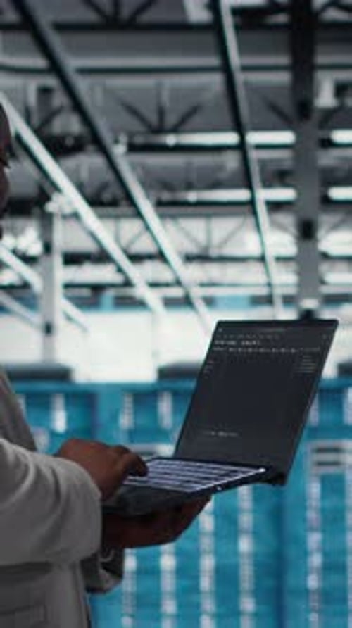 Ingénieur d'infrastructure de salle de serveurs vidéo verticale écrivant des scripts de flux de travail automatisés à l'aide d'un logiciel