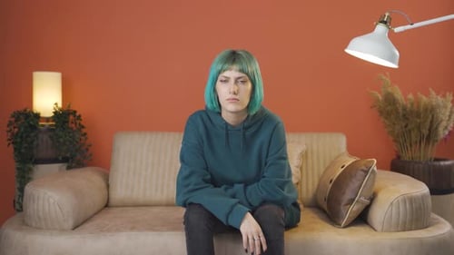 Young Adult with Teal Hair Sits on Couch
