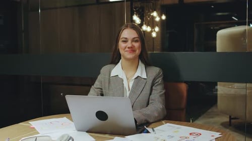 A Confident Young Businesswoman with a Warm Smile Sits at Her Organized Desk in a Modern Office