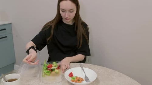Young Woman Emptying a Plastic Container of Fresh Salad Onto a Plate