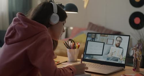 Teenage Girl Learning English Online in Virtual School Watching Video Lecture and Writing Notes at