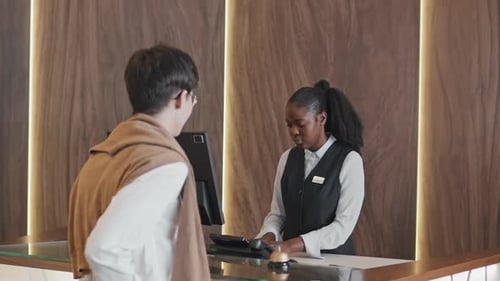 Black Woman Working At Reception Desk In Hotel