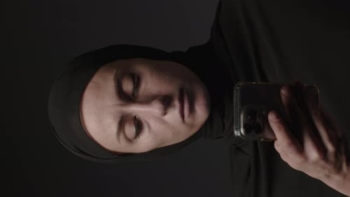 Vertical Video of Woman in Black Muslim Headscarf Talking on Mobile Phone