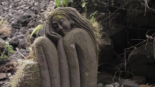 Figura de piedra de una niña en el musgo de la jungla