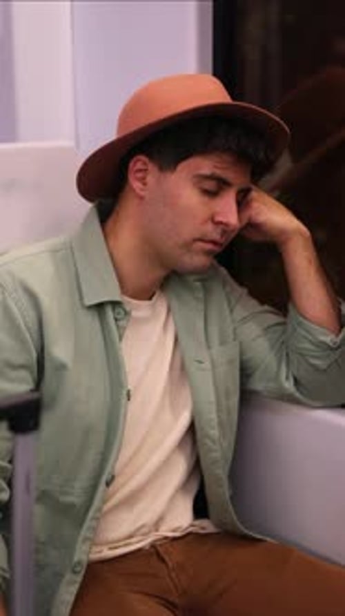 vertical close-up of tired traveler with hat asleep resting on window during long journey
