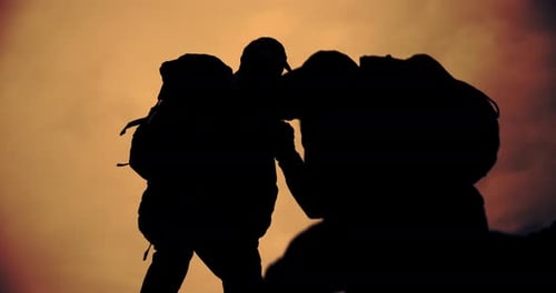 Sunset, mountain and silhouette of people helping on cliff for support or view in nature