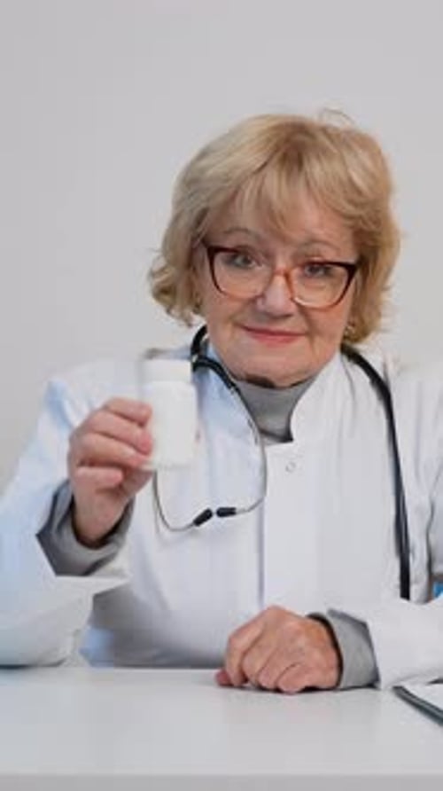 Senior Female Doctor Holding Pill Bottle