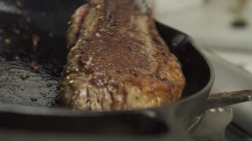 Frying meat steak inside frying pan. Close up slow motion shot.