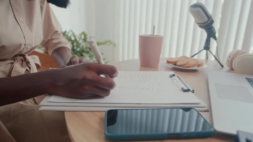 Unrecognizable Journalist Writing Notes while Preparing for Interview in Studio