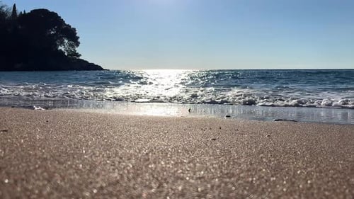 Eine Meereswelle rollt an einem sonnigen Tag auf eine saubere Sandküste
