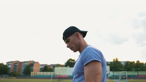 Portrait of Young Muscular Man in Backwards Cap and Blue Tshirt Standing at City Stadium Circular