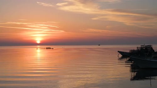 Wooden fisherman boats floating on calm moving water waves with reflection of colorful twilight sunr