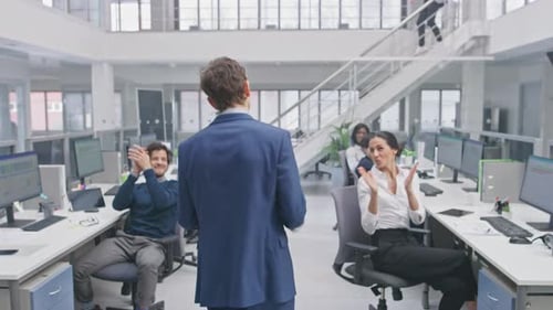 Der junge, glückliche Geschäftsführer im Anzug wird von seinen Kollegen bejubelt und gefeiert