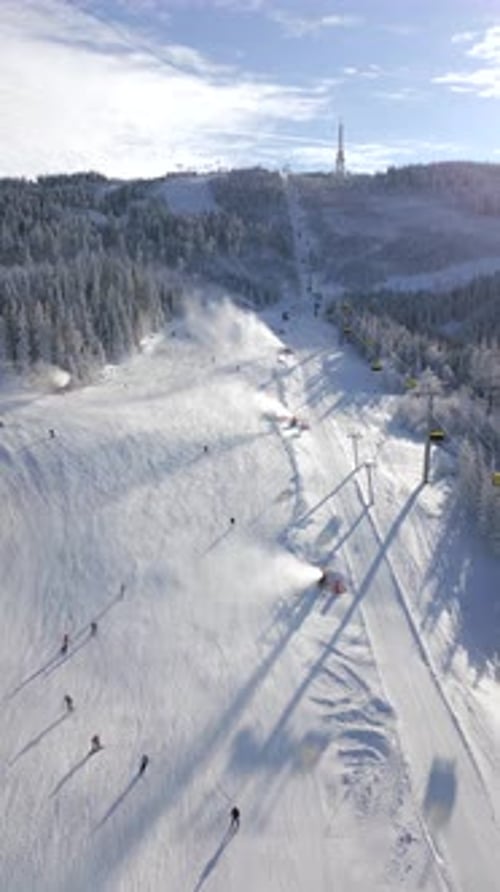 Aerial View of a Ski Lift with Skiers and Snowboarders on a Snowy Slope