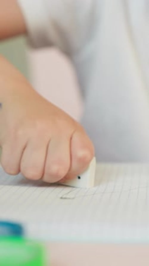 Child Erasing Mistake on Paper at Desk