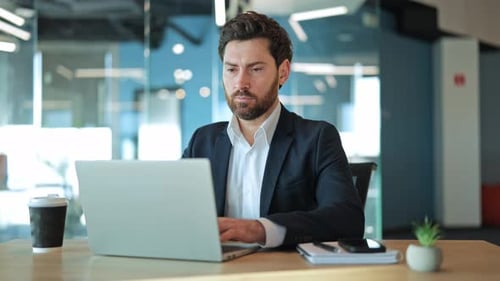 Focused Professional Working on Laptop in Modern Office