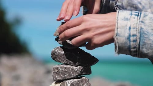 Woman Stacks Zen Stones on an Island. This shot captures a slow motion detail close up of her placin