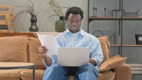 Man Uses Laptop at Home on Brown Couch
