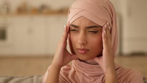 Worried Woman Wearing Head Covering, Resting Hands on Temples