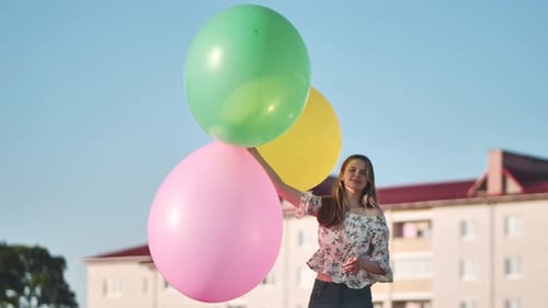 A Girl Happily Poses with Large with Colorful Balloons in the City