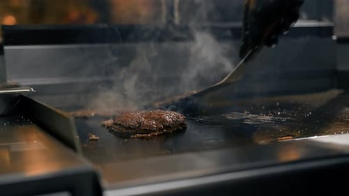 The chef in the kitchen of the restaurant makes cutlets for burgers - smash burger beefsteak
