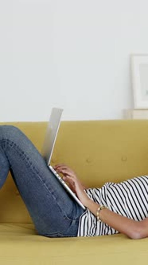 Woman Lying on Couch Using Laptop Computer Indoors