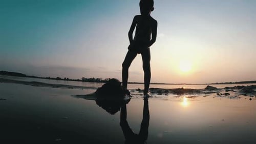 Silhouette Little Boy construye un castillo de arena al atardecer