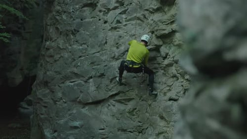 Young Bearded Climber Wearing Helmet Climbing Down the Limestone Cliff Alpinist Carefully Climbing