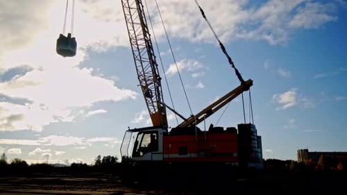 Toma de ángulo bajo de una grúa de compactación de tierra ocupada martillando terreno a lo largo de un campo en
