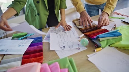Stylists Hands Choosing Cloth Samples for Fashion Collection in Office Closeup