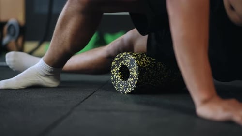 Athletic Man Using Foam Roller for Leg Exercise