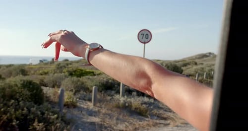 A person's arm is extended out of a car window, enjoying the breeze on a road trip with copy space