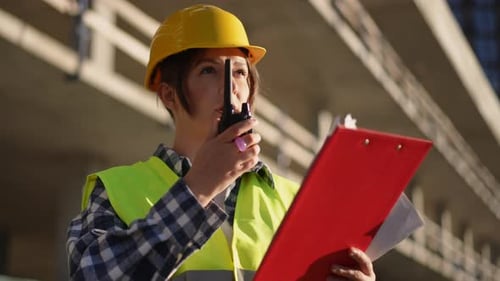 Woman Construction Worker Using Walkie Talkie at Site
