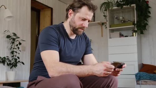 Man Sits Indoors Using Smartphone