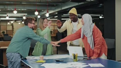 Diverse Team Stacking Hands in Modern Office