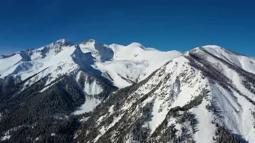 Air flight through mountain clouds over beautiful snow-capped peaks of mountains and glaciers.