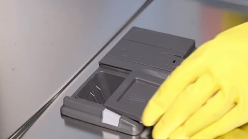 Closeup of a Woman Putting a Tablet of Dishwasher Detergent Into a Box