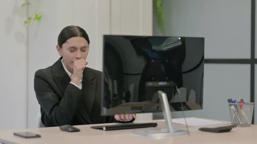 Young Woman Coughing at Desk in Office Environment