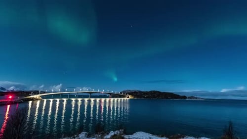 time lapse of northern lights over sommaroy village on island and bridge during winter night in norw