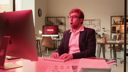 Man in Office Reacts to Error Message on Computer