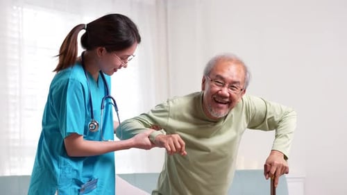 Nurse Helping Senior Man Walk with Cane Indoors