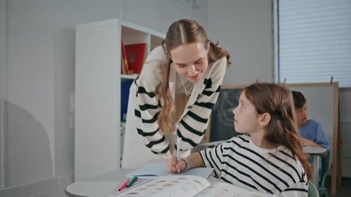 Teacher Helping Young Girl with Schoolwork in Classroom
