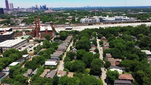 Fly over houses in residential suburbs of metropolis. Heavy freight train slowly moving on railway l