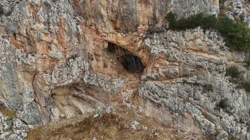 rustic cliff side view of a rugged mountain in spain as the view narrows in on a smaller cave