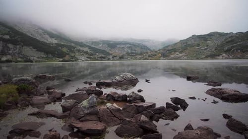 O lago de peixes em Rila Mountain, Bulgária. Com uma névoa mística sobre o lago.