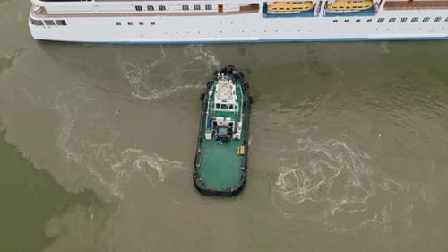 Tug boat assisting cruise ship arrival to port. Bottom sediment mixed by vessel propulsion. High alt
