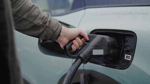 Nahaufnahme der männlichen Hand Stecken Sie den Stecker ein, um das Elektroauto aufzuladen